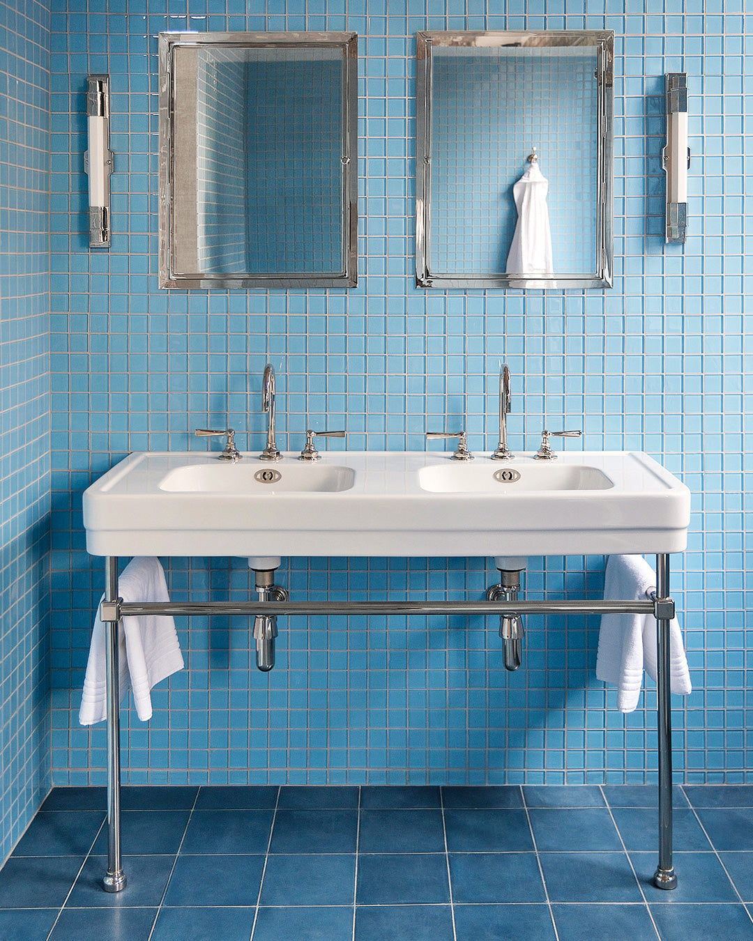 Bathroom with a double sink vanity against a blue glass tiled wall.