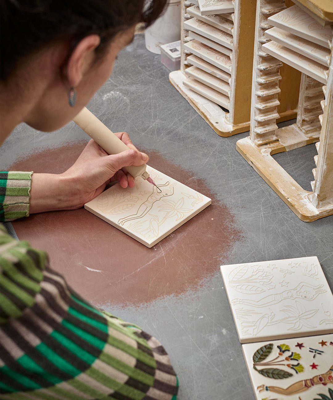 Person working on a ceramic piece with a tool in a workshop setting