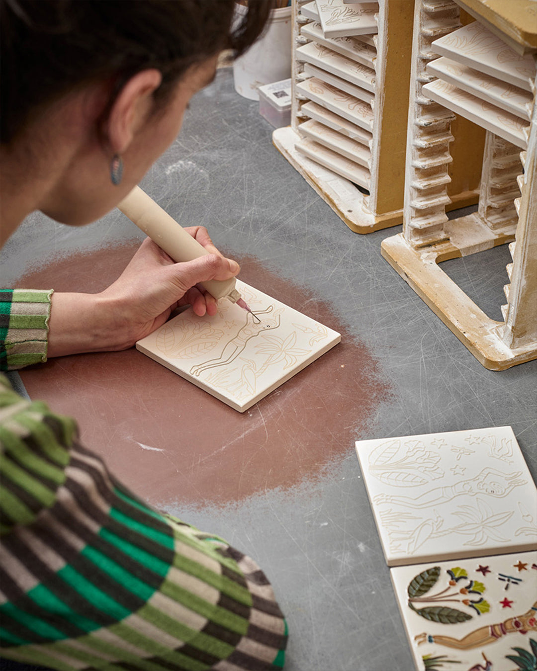 Person working on a ceramic piece with a tool in a workshop setting
